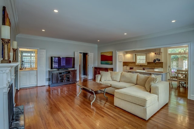 living area with crown molding, light wood-type flooring, and recessed lighting