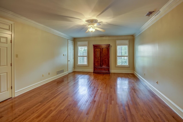 interior space with ceiling fan, ornamental molding, wood finished floors, and visible vents