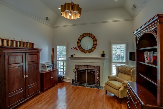 living area featuring light wood-type flooring, a high end fireplace, and visible vents