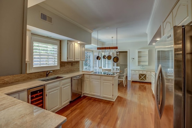 kitchen with beverage cooler, stainless steel appliances, a peninsula, visible vents, and light countertops