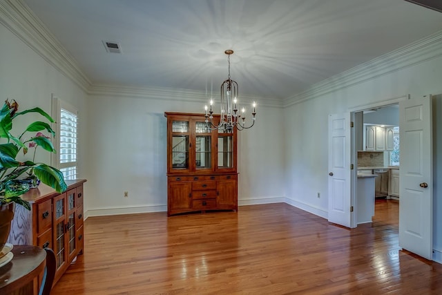 dining space with baseboards, light wood-type flooring, visible vents, and crown molding