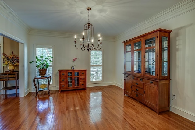 dining space featuring a notable chandelier, light wood-style flooring, baseboards, and crown molding