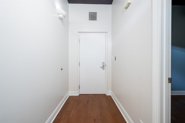 hallway featuring dark wood-type flooring, visible vents, and baseboards