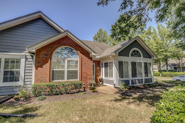 view of front of house with a sunroom and a front yard