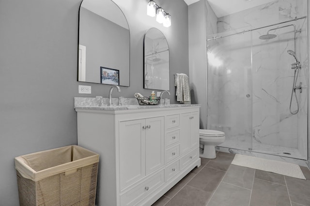 bathroom with tile patterned flooring, vanity, tiled shower, and toilet