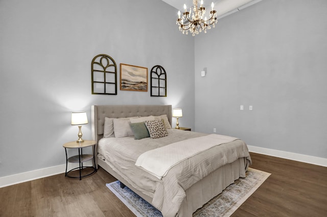 bedroom with a notable chandelier and dark wood-type flooring