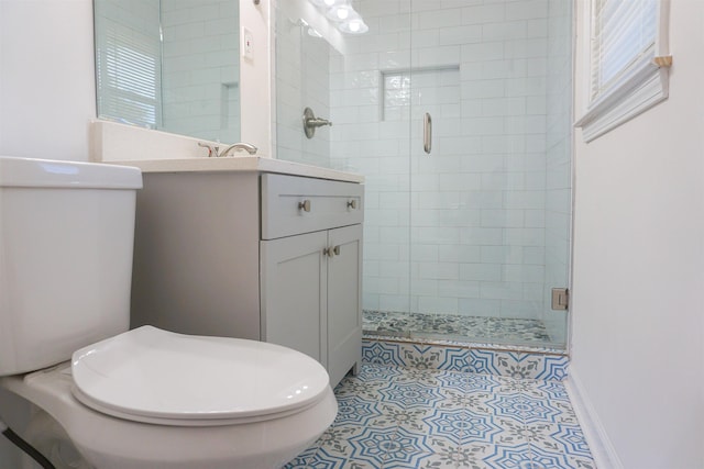 full bathroom featuring toilet, vanity, a shower stall, baseboards, and tile patterned floors