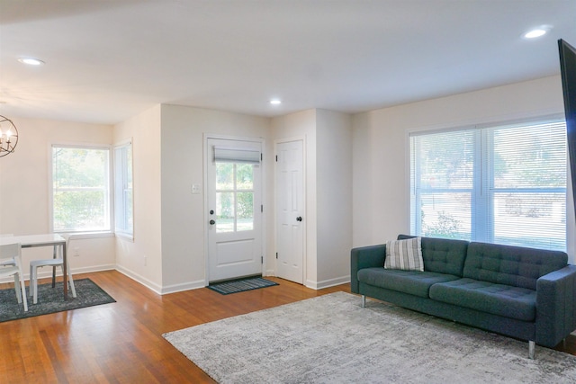 living room featuring a chandelier, recessed lighting, baseboards, and wood finished floors