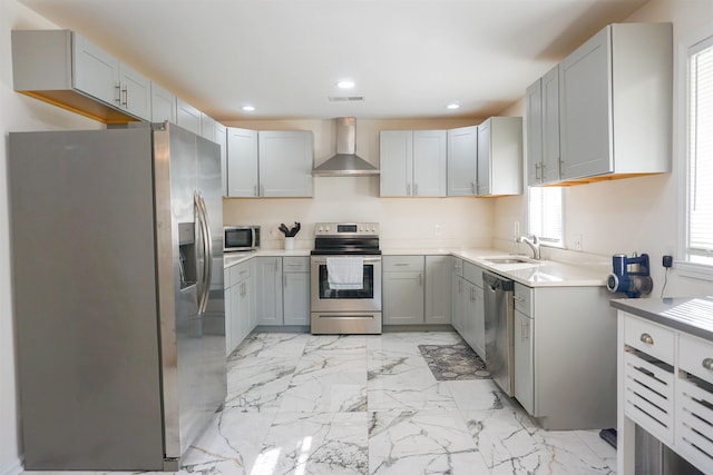 kitchen featuring marble finish floor, stainless steel appliances, gray cabinets, light countertops, and wall chimney exhaust hood