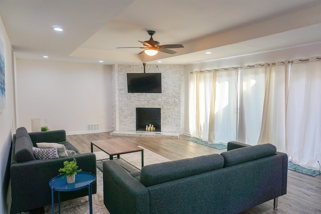 living room with a fireplace, wood finished floors, visible vents, and recessed lighting