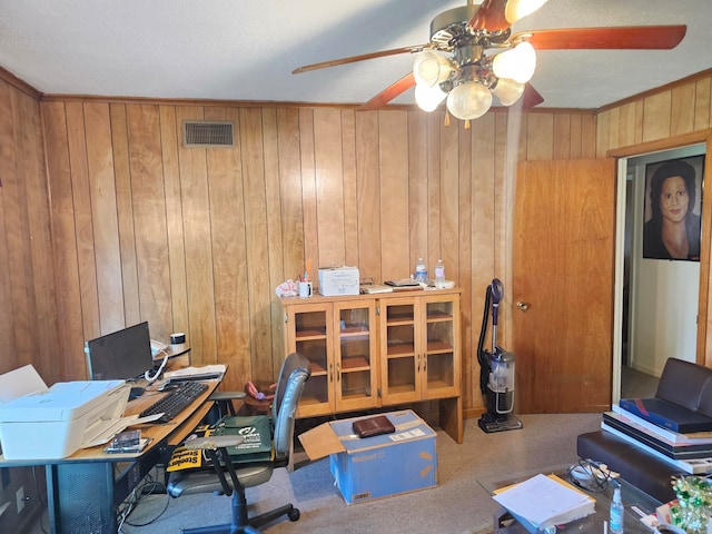 office space with wood walls, ceiling fan, and carpet flooring