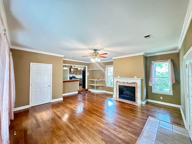 unfurnished living room with a tiled fireplace, ornamental molding, hardwood / wood-style floors, and ceiling fan