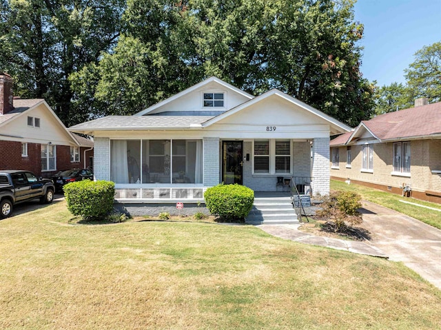 bungalow featuring covered porch, brick siding, and a front lawn