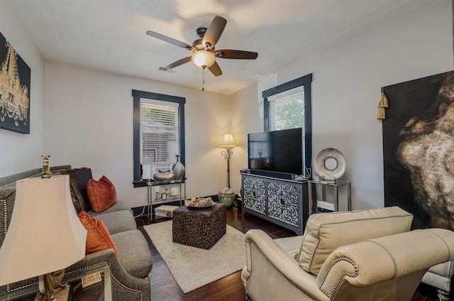 living area with dark wood-type flooring, plenty of natural light, and ceiling fan