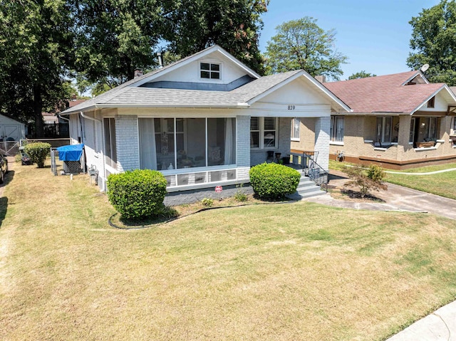 view of front of property with brick siding, a front lawn, and a shingled roof