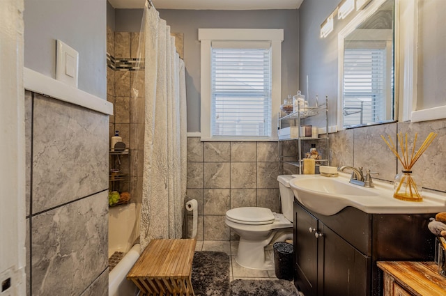 full bathroom with toilet, a wainscoted wall, tile patterned flooring, vanity, and tile walls