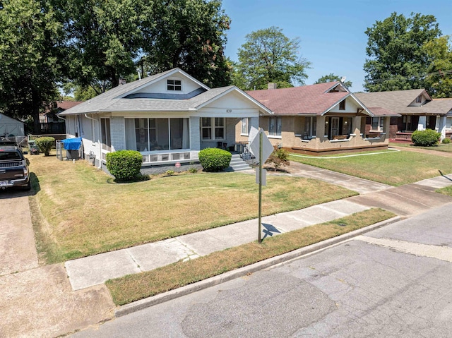 view of front of house featuring a porch, brick siding, a chimney, and a front lawn