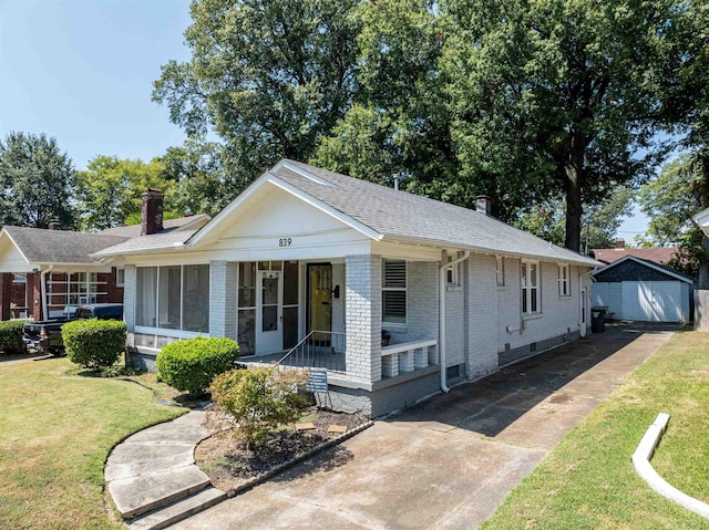 view of front facade featuring a porch, a chimney, a front lawn, and brick siding