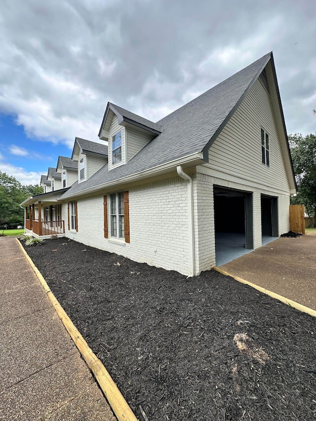 view of property exterior featuring brick siding and a shingled roof