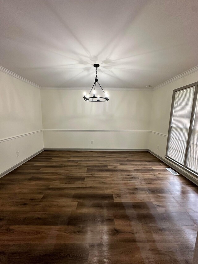 unfurnished dining area featuring dark wood finished floors, a notable chandelier, and ornamental molding