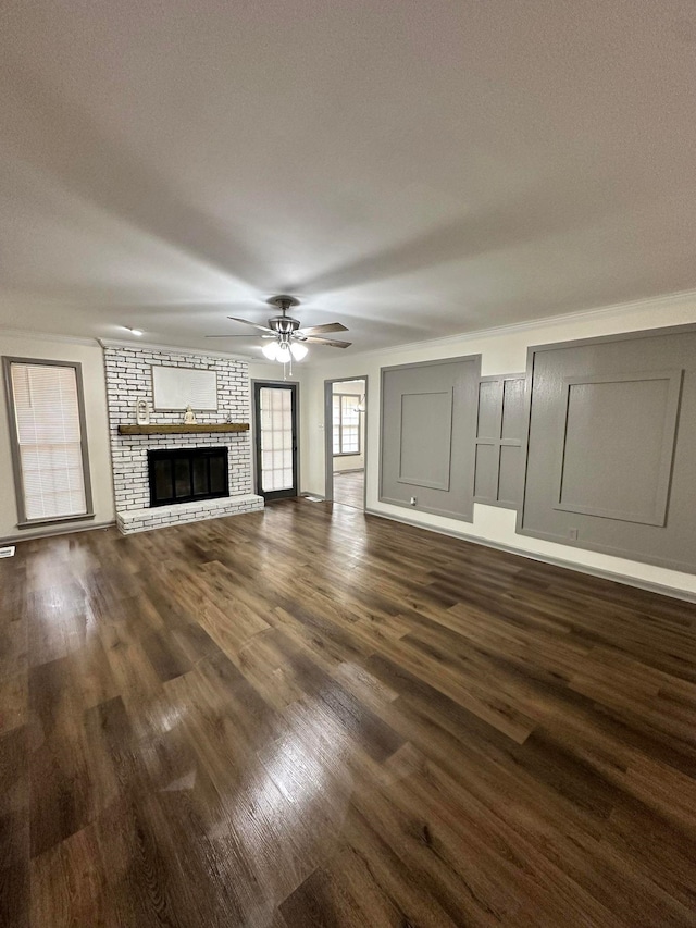 unfurnished living room with a ceiling fan, a brick fireplace, and dark wood-style flooring