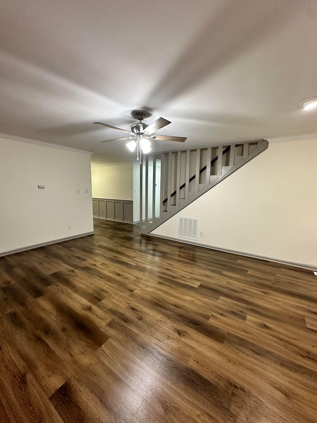 unfurnished living room with ornamental molding, ceiling fan, baseboards, dark wood-style flooring, and visible vents