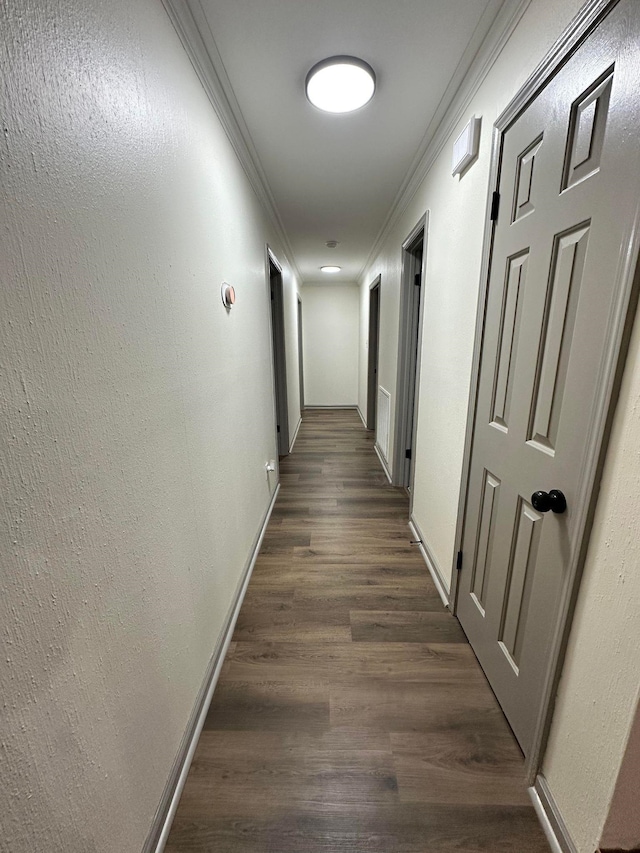 hall with dark wood-style flooring, ornamental molding, and baseboards