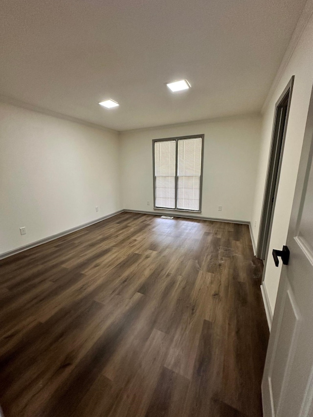 spare room featuring baseboards and dark wood-type flooring