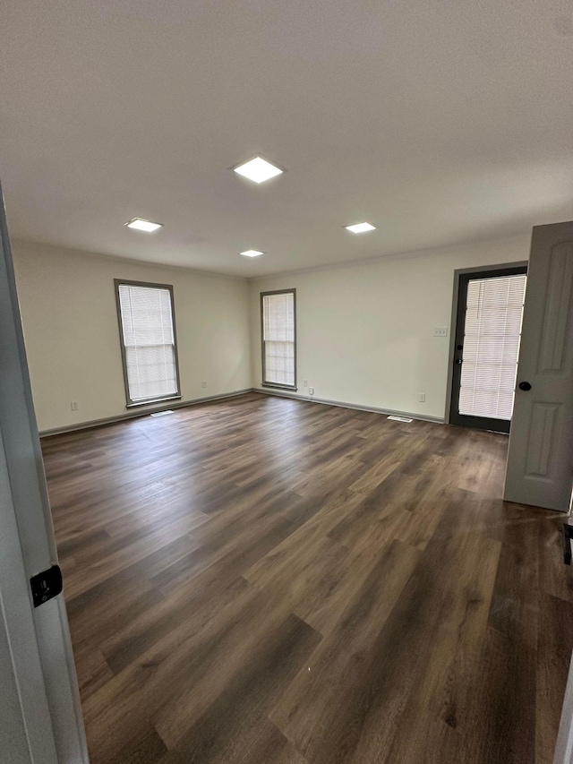 unfurnished room featuring dark wood finished floors, a wealth of natural light, and baseboards
