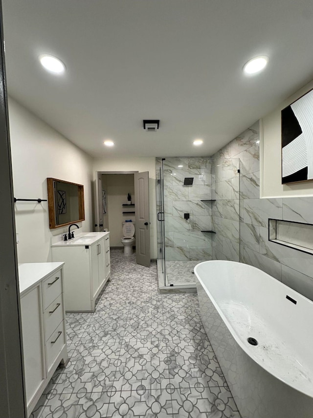 bathroom featuring a stall shower, vanity, a freestanding bath, toilet, and recessed lighting
