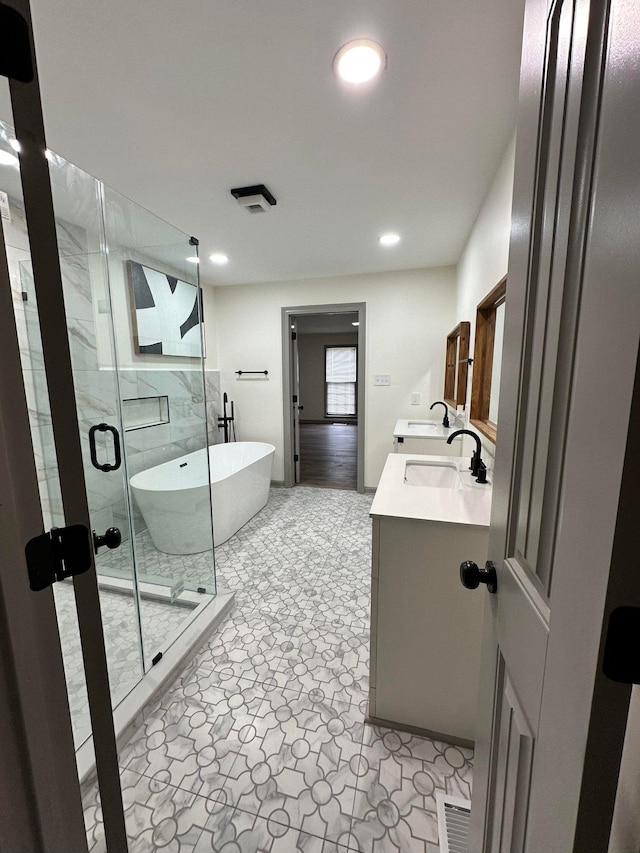 bathroom featuring a shower stall, a freestanding tub, a sink, and double vanity