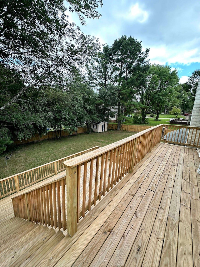 deck featuring a lawn, a fenced backyard, an outdoor structure, and a storage shed
