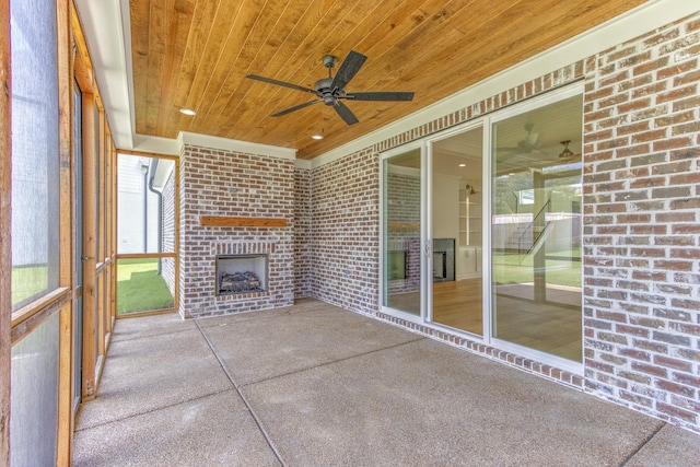 unfurnished sunroom featuring ceiling fan, wood ceiling, and an outdoor brick fireplace