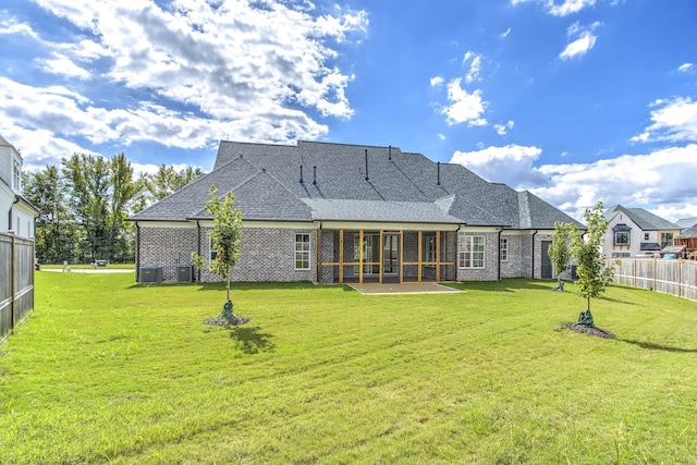 rear view of property with a patio, a lawn, and a sunroom