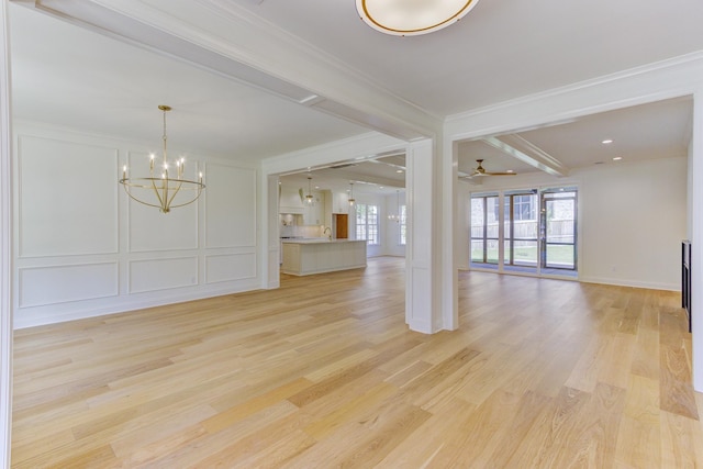 unfurnished living room with ceiling fan with notable chandelier, light hardwood / wood-style floors, and ornamental molding