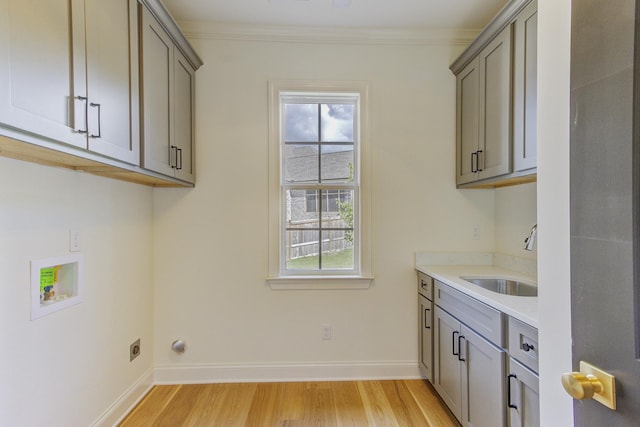 laundry room featuring cabinets, washer hookup, crown molding, sink, and light hardwood / wood-style flooring