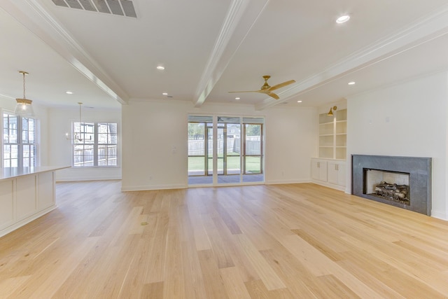 unfurnished living room with light wood-type flooring, ornamental molding, ceiling fan, built in features, and beamed ceiling