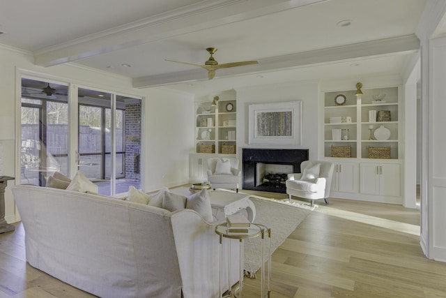 living room with built in shelves, ornamental molding, a high end fireplace, and light hardwood / wood-style flooring