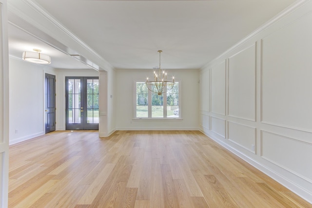 unfurnished dining area with a chandelier, french doors, light hardwood / wood-style flooring, and crown molding