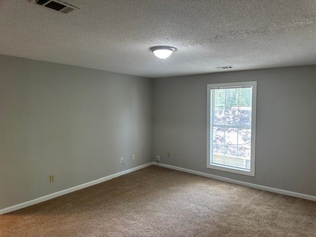 unfurnished room featuring carpet and a textured ceiling