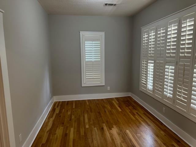 empty room with a textured ceiling and dark hardwood / wood-style floors