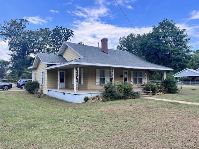 farmhouse inspired home featuring a chimney, fence, a shingled roof, covered porch, and a front yard