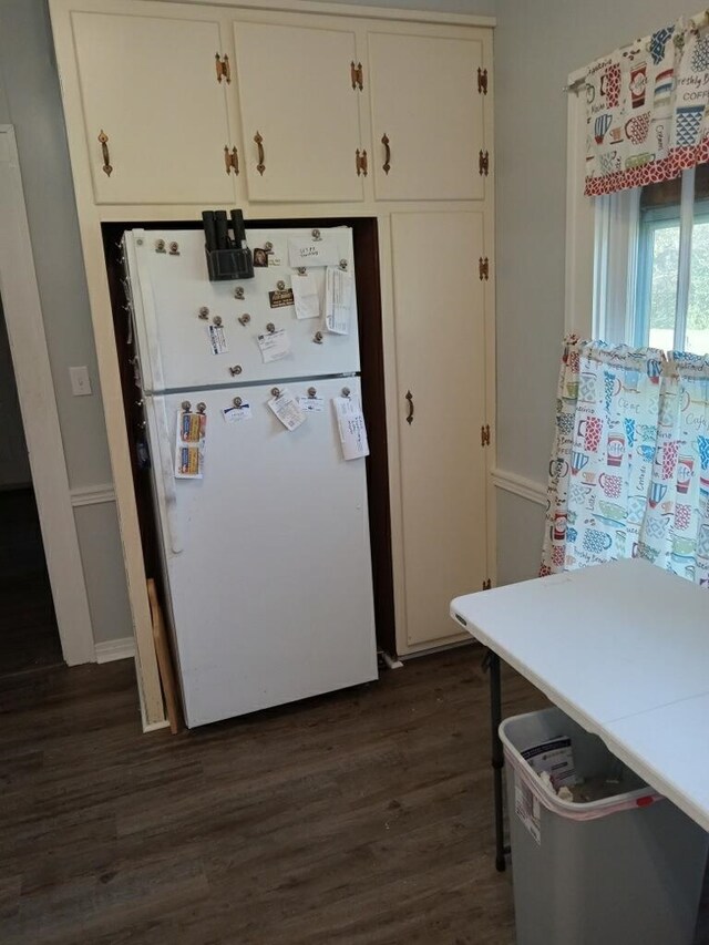 kitchen featuring dark wood-type flooring, freestanding refrigerator, and white cabinetry