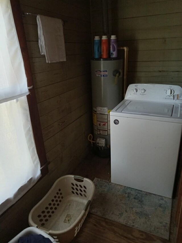 clothes washing area featuring water heater, laundry area, washer / dryer, and wooden walls