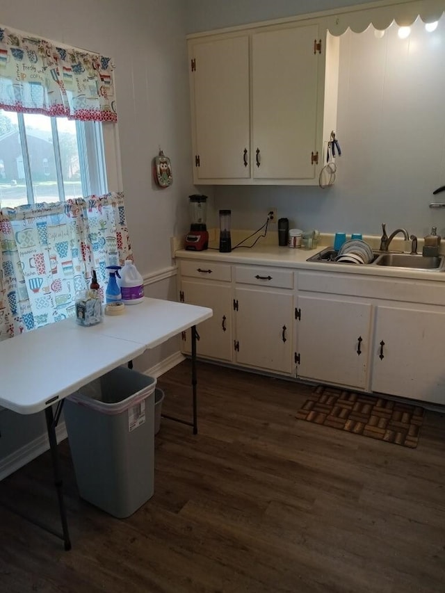 kitchen with dark wood-type flooring, light countertops, white cabinetry, and a sink