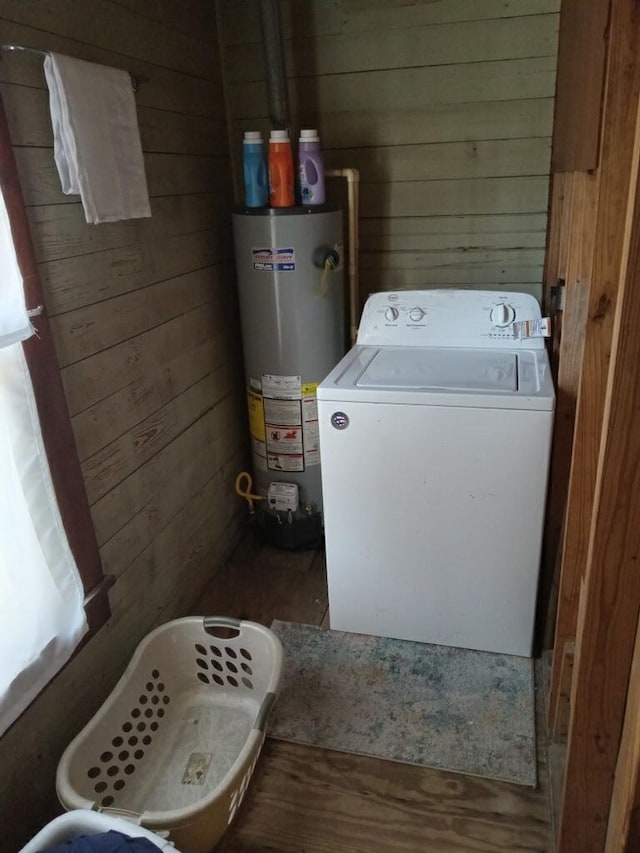 laundry area featuring laundry area, wood walls, gas water heater, and washer / dryer