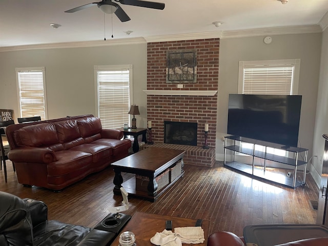 living room with crown molding, ceiling fan, a brick fireplace, and dark hardwood / wood-style flooring