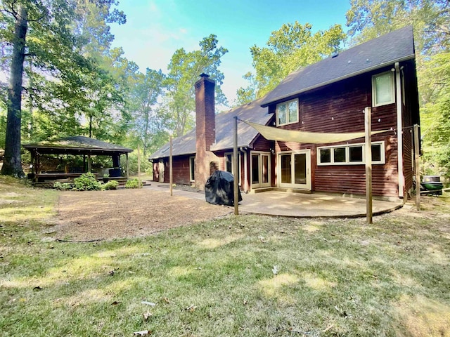 rear view of house featuring a gazebo, a patio, a lawn, and a chimney