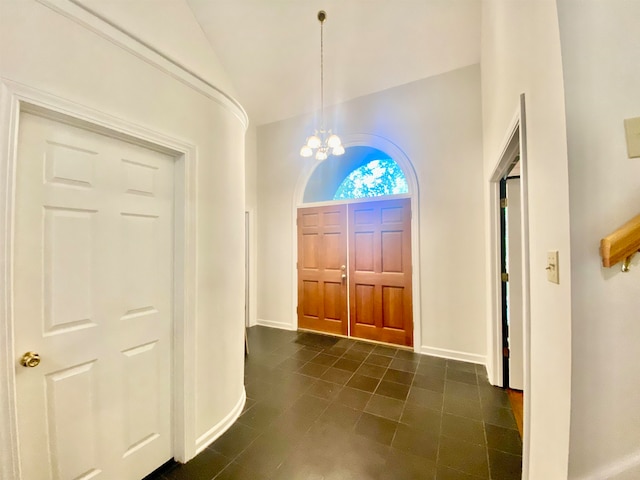 entrance foyer featuring vaulted ceiling, an inviting chandelier, and dark tile patterned flooring