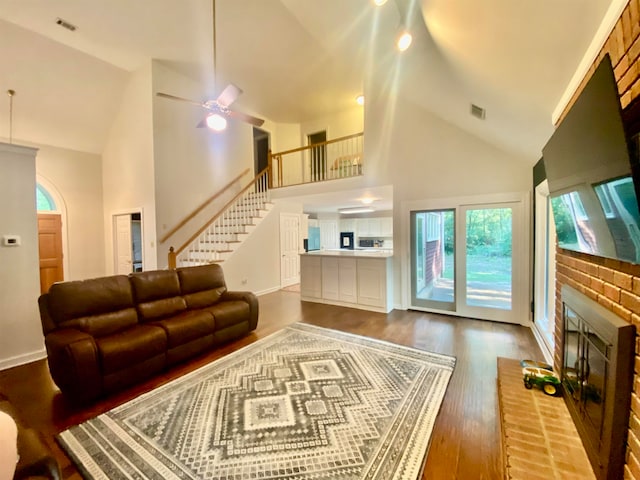 living room featuring a fireplace, high vaulted ceiling, wood-type flooring, and ceiling fan